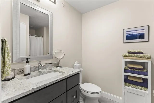 a bathroom with a granite countertop sink a toilet and a mirror