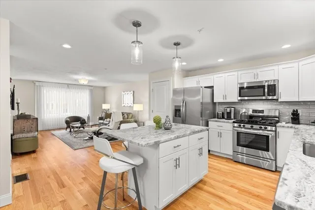 a kitchen with stainless steel appliances kitchen island granite countertop a sink dishwasher stove and oven with wooden floor