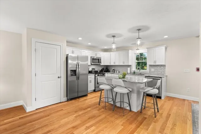 a living room with stainless steel appliances kitchen island granite countertop furniture and a wooden floor