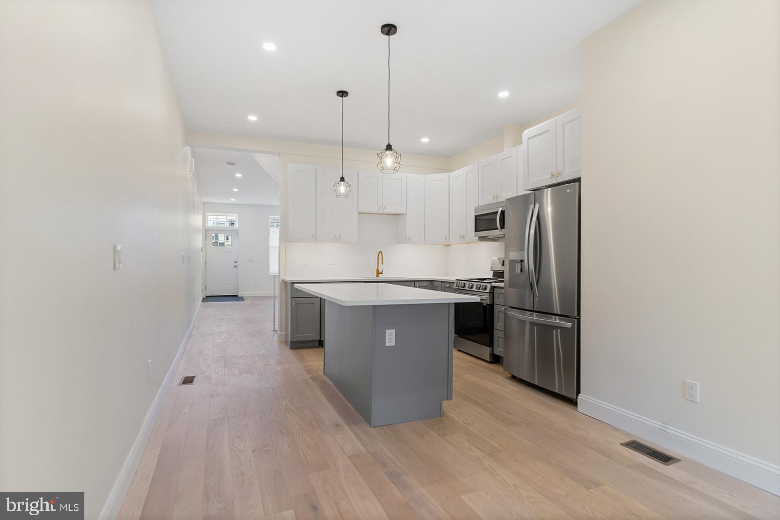 1644 North 6th Street Philadelphia, PA 19122 - Photo 12 of 52 a large kitchen with stainless steel appliances kitchen island granite countertop a refrigerator a sink dishwasher a oven and a dining table with wooden floor