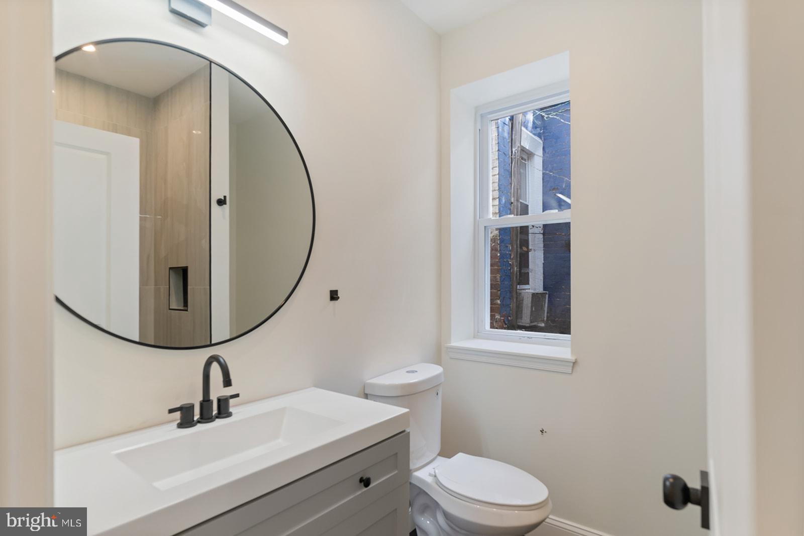 1644 North 6th Street Philadelphia, PA 19122 - Photo 26 of 52 a bathroom with a sink a mirror a toilet and a window