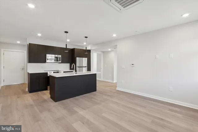 a large kitchen with a sink and dishwasher a refrigerator with wooden cabinets