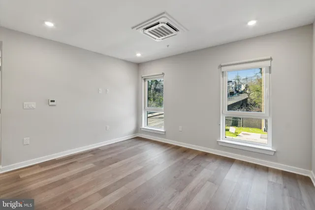 an empty room with wooden floor and windows