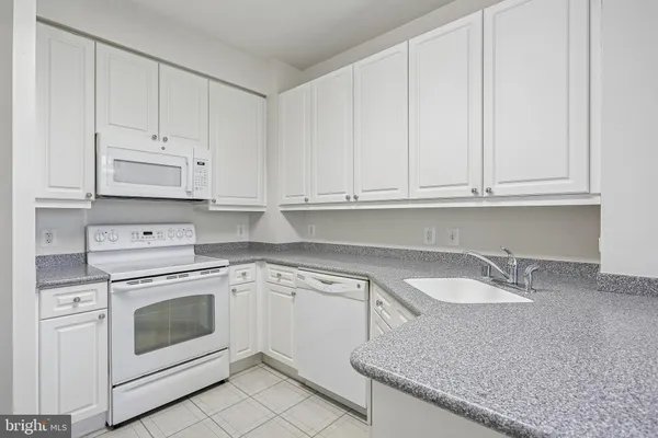 a kitchen with granite countertop white cabinets and white appliances