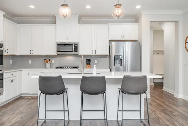 a kitchen with stainless steel appliances granite countertop a stove a refrigerator a sink a dining table and chairs with wooden floor