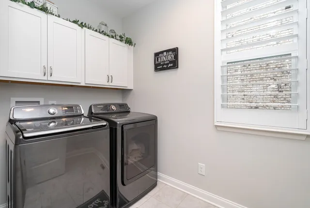 a utility room with stainless steel appliances white cabinets and a window
