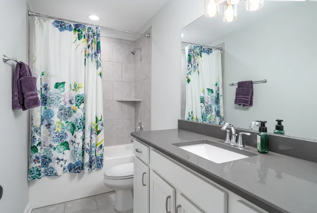 a bathroom with a granite countertop sink a toilet a mirror a vanity and shower