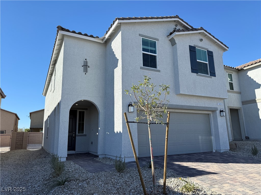 Mediterranean / spanish home featuring a tile roof, an attached garage, and stucco siding
