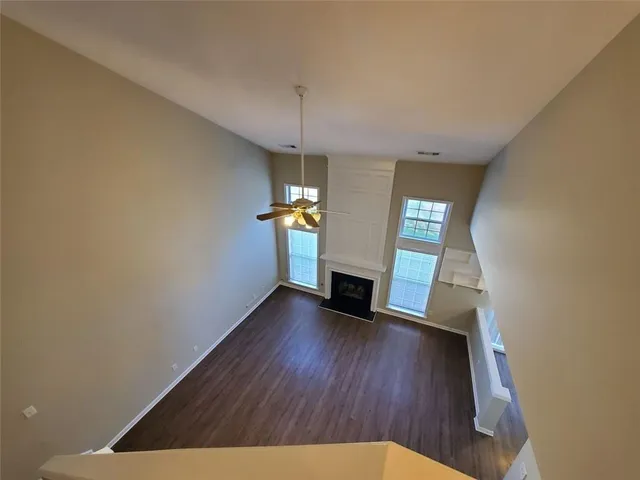 an empty room with windows and ceiling fan