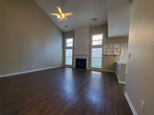 an empty room with wooden floor fireplace and windows