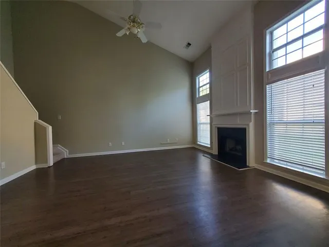 an empty room with wooden floor fireplace and windows