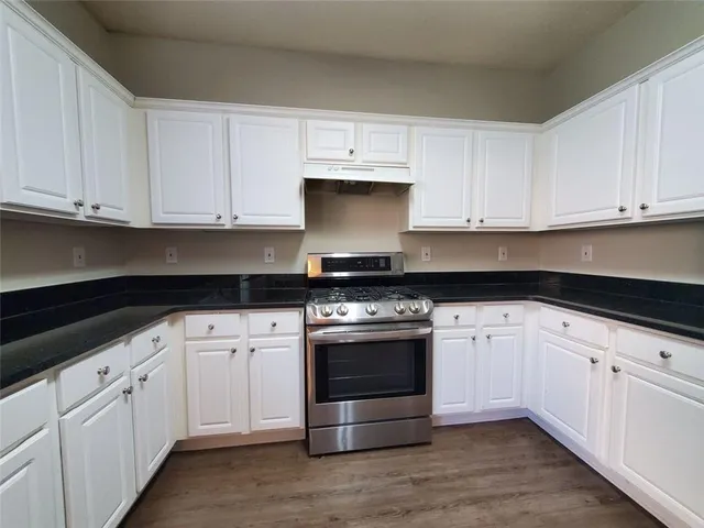 a kitchen with granite countertop white cabinets and stainless steel appliances