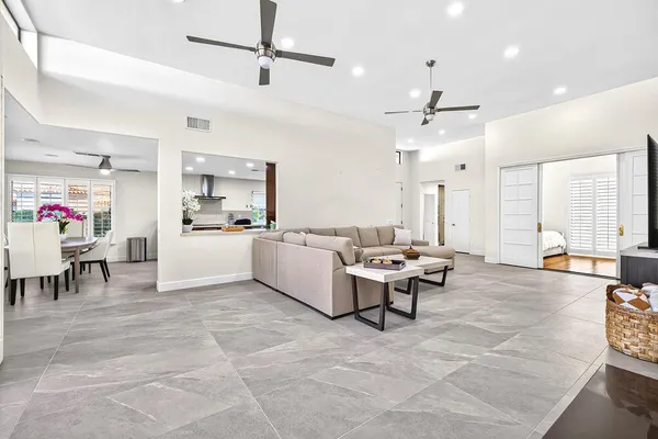 a living room with couches and kitchen view with wooden floor