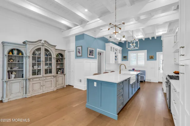 a large white kitchen with stainless steel appliances granite countertop a lot of counter space and wooden floor
