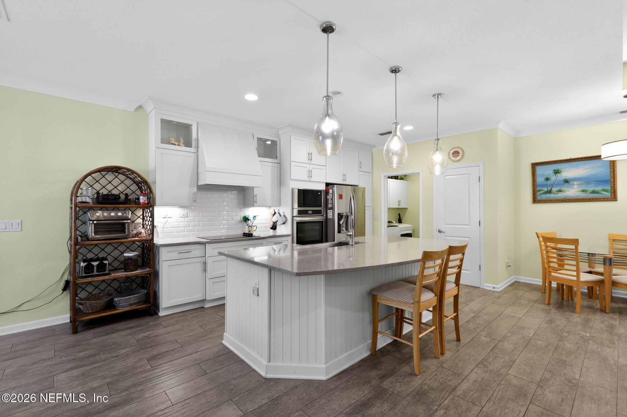 96017 Breezeway Court Yulee, FL 32097 - Photo 8 of 30 a kitchen with stainless steel appliances a dining table chairs stove and refrigerator