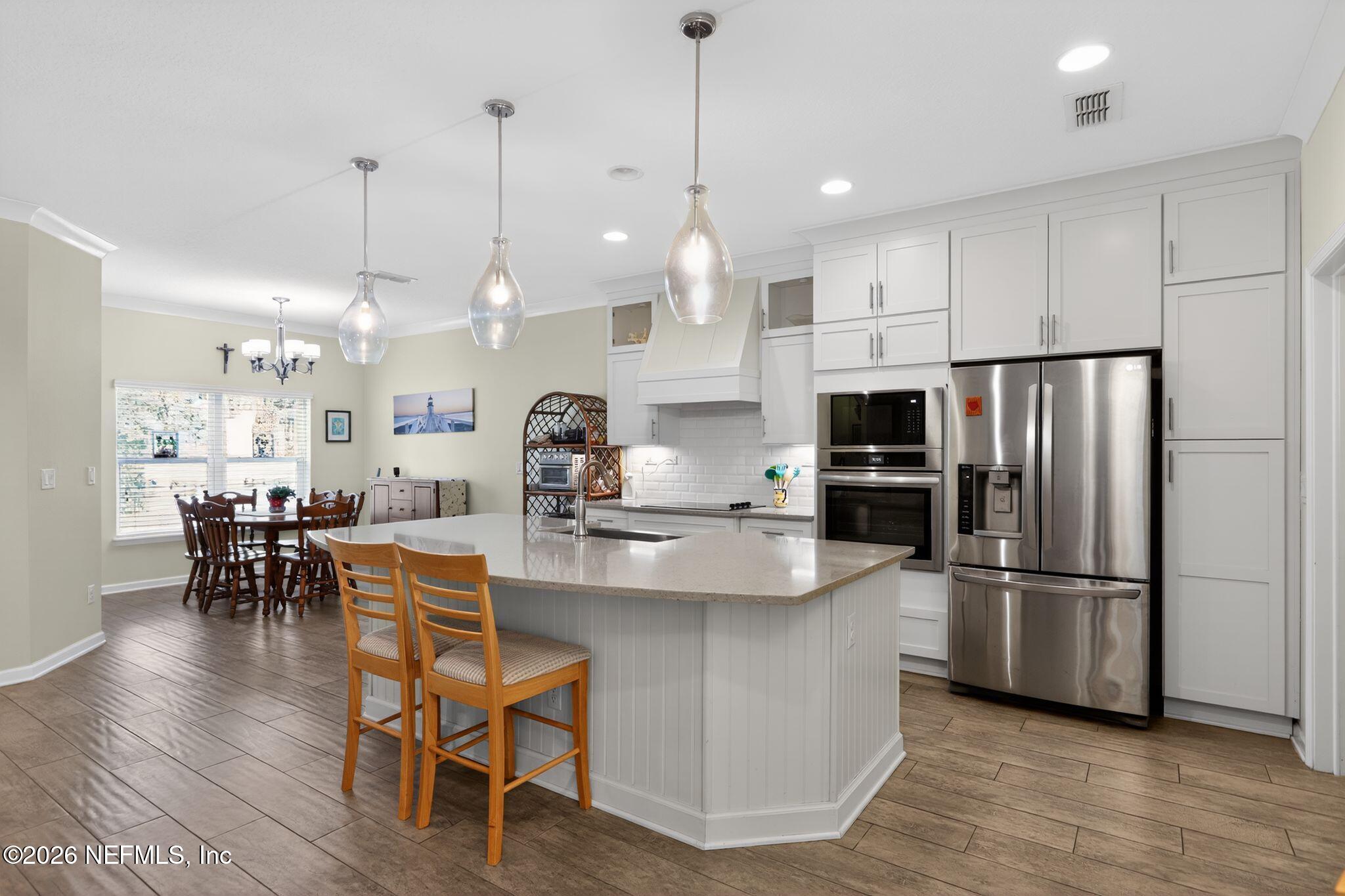 96017 Breezeway Court Yulee, FL 32097 - Photo 10 of 30 a kitchen with stainless steel appliances kitchen island a refrigerator a stove a dining table and chairs