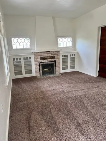 a view of an empty room with a fireplace and a window