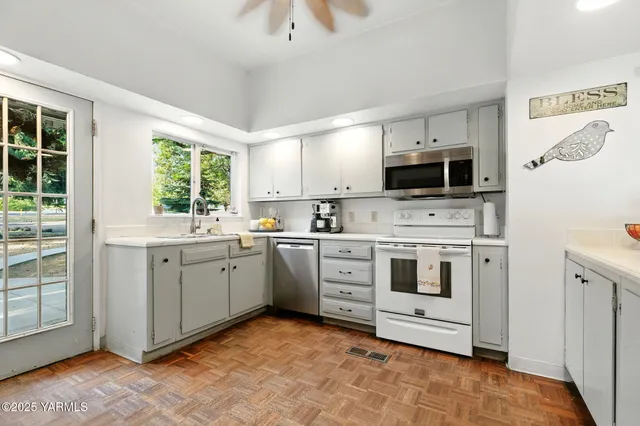 a kitchen with white cabinets appliances and a window