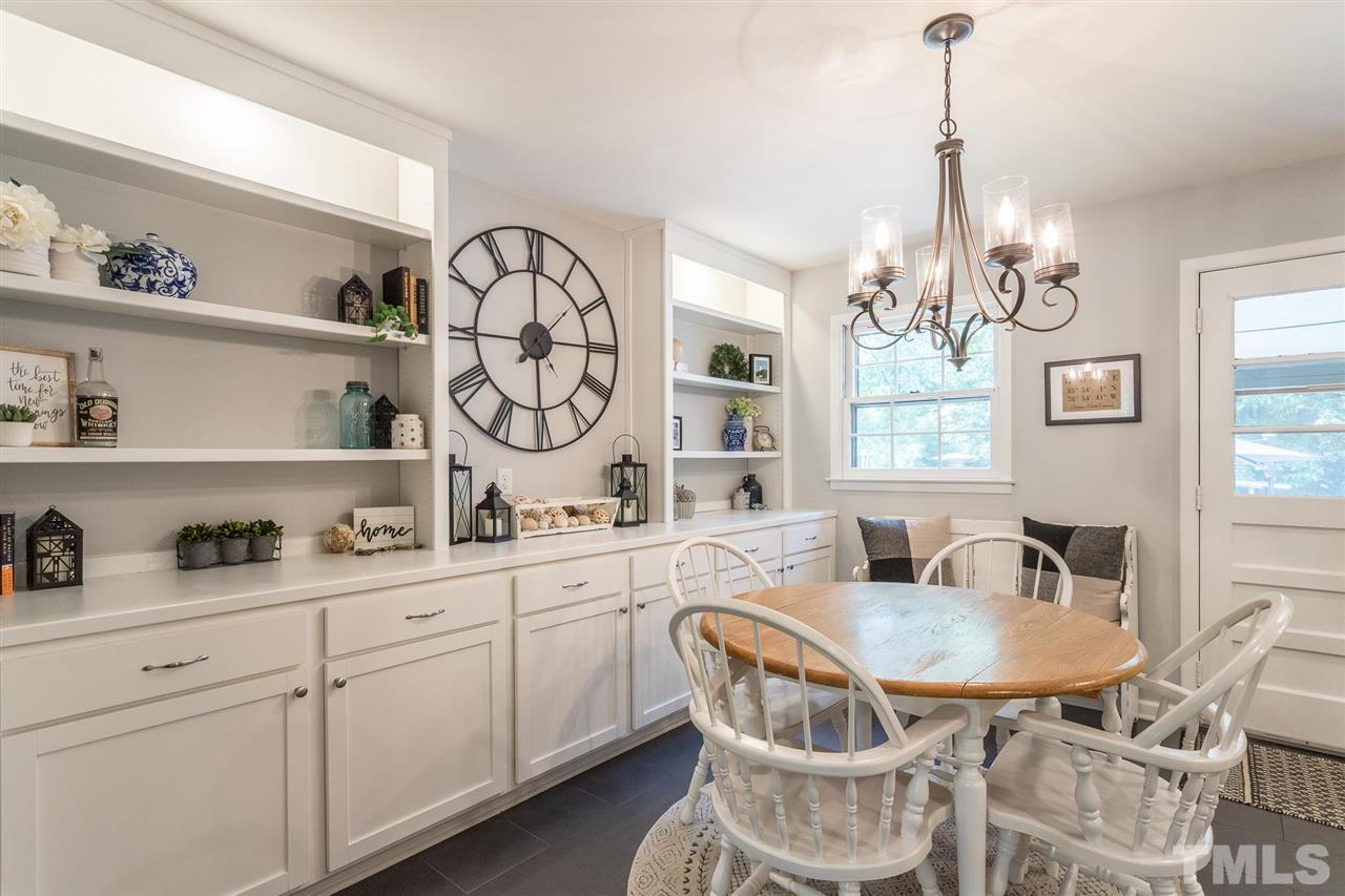 4802 Revere Road Durham, NC 27713 - Photo 14 of 29 a kitchen with a dining table chairs and white cabinets