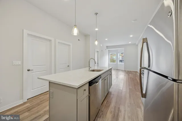 a kitchen with stainless steel appliances a refrigerator a sink dishwasher with a dining table and wooden floor