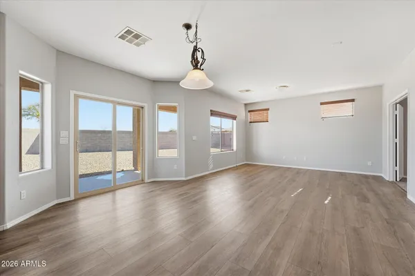 a view of an empty room with wooden floor and windows