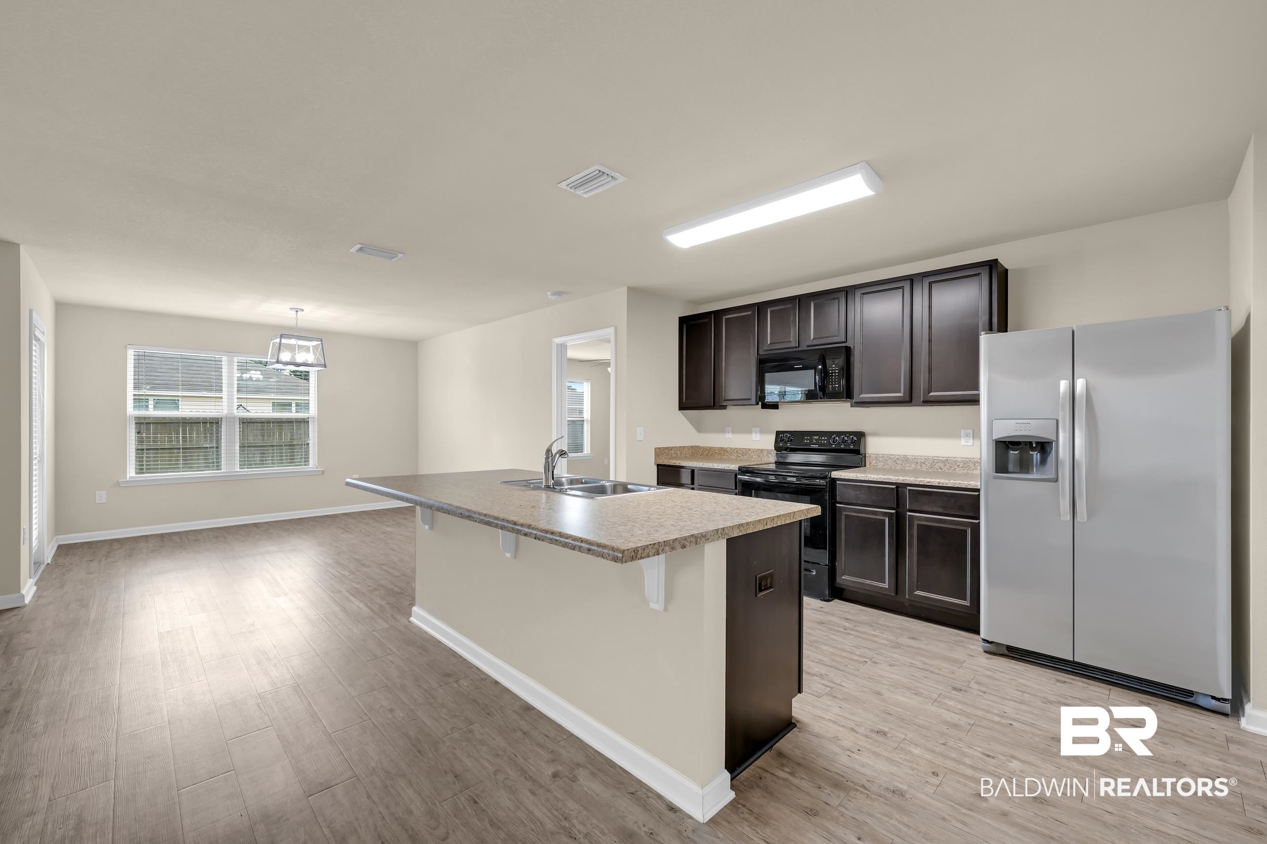 17344 Harding Drive Foley, AL 36535 - Photo 3 of 46 Kitchen featuring a center island with sink, dark wood-finish cabinetry, stainless steel refrigerator, and wood-look flooring