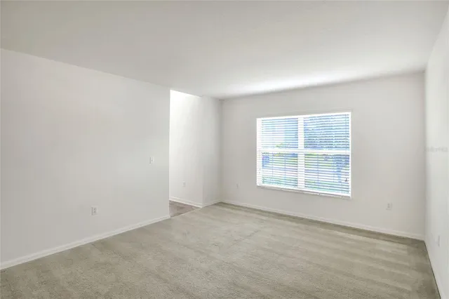 an empty room with windows and ceiling fan