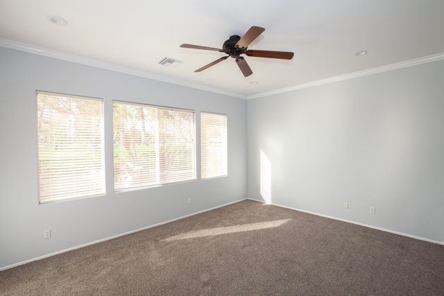 a view of a livingroom with a ceiling fan & windows
