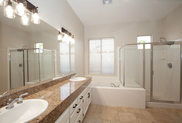 a bathroom with a granite countertop tub double vanity sink and a mirror