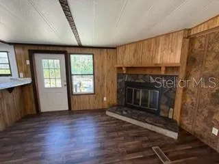 an empty room with wooden floor fireplace and windows