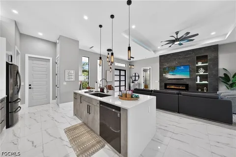 a large kitchen with stainless steel appliances a stove a sink dishwasher a refrigerator white cabinets and wooden floor