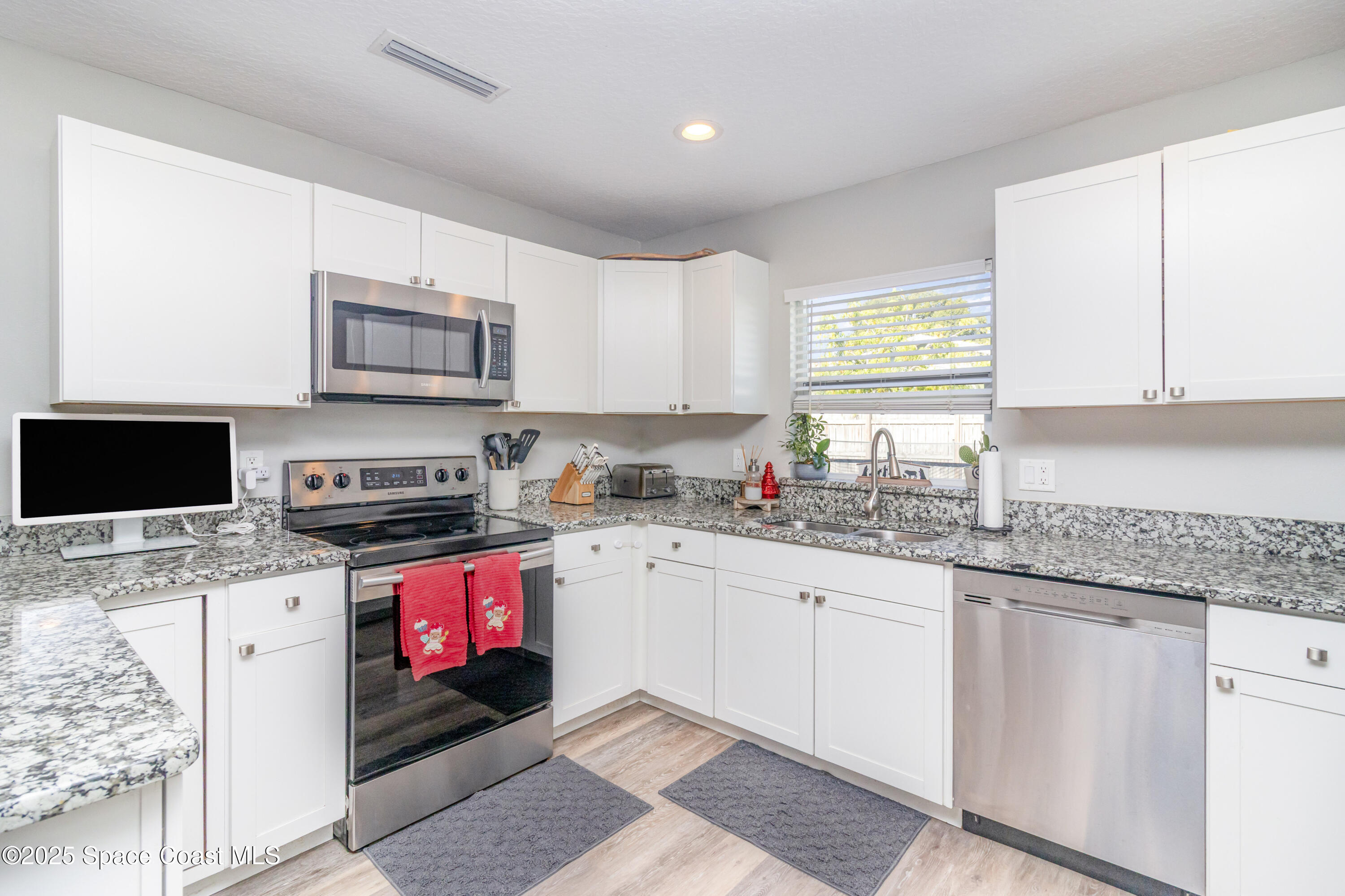 964 Bucknell Place Rockledge, FL 32955 - Photo 7 of 30 a kitchen with stainless steel appliances granite countertop a stove sink and microwave