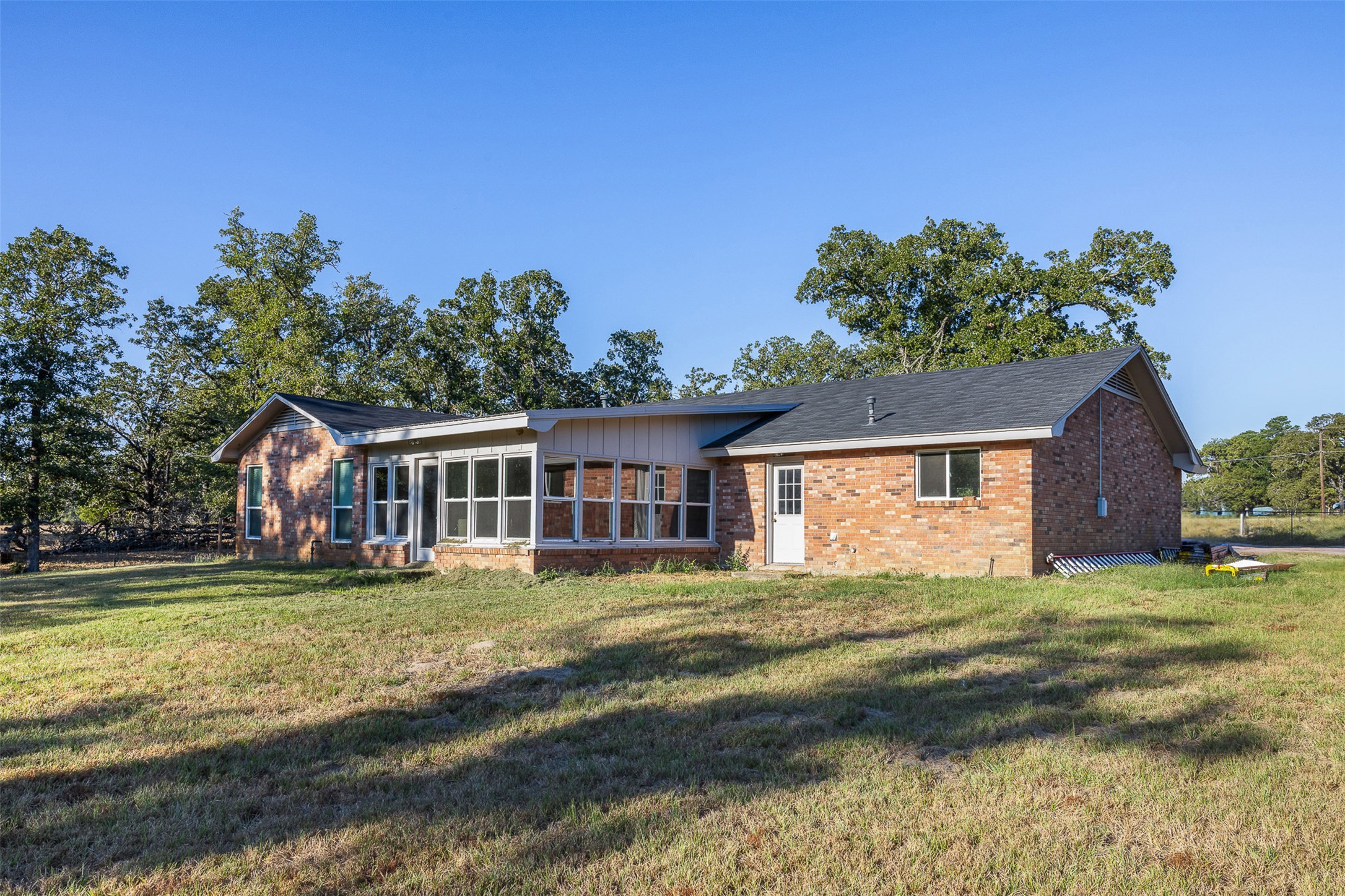 139 Farm To Market 696 Elgin, TX 78621 - Photo 2 of 27 Rear view of property with brick siding, a yard, and a sunroom