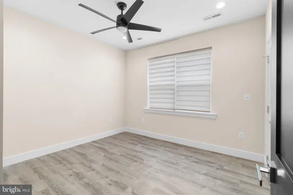 a view of empty room with wooden floor and fan