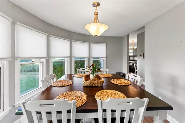 a view of a dining room with furniture a chandelier and large windows