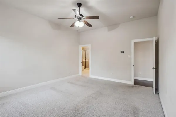 an empty room with a chandelier fan and a bathroom