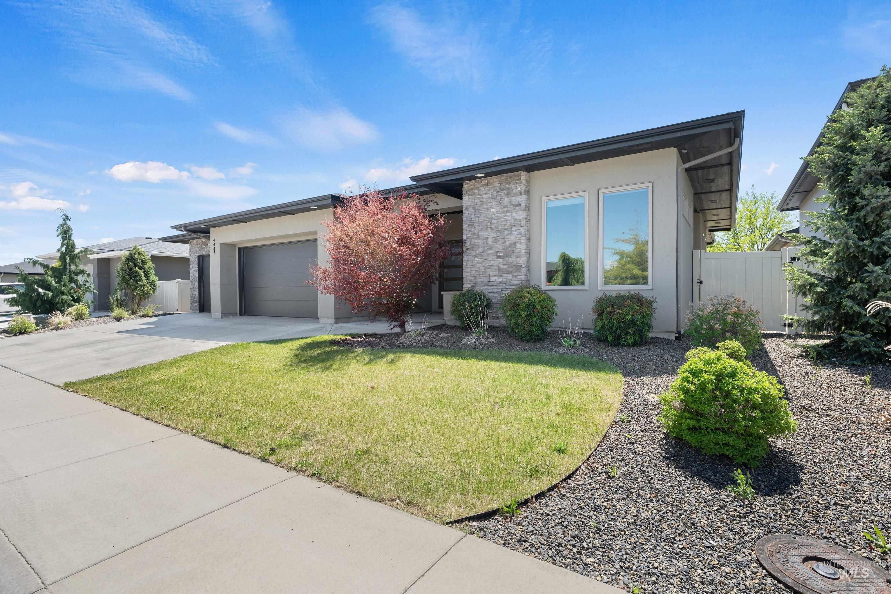 4447 East Copper Point Drive Meridian, ID 83642 - Photo 2 of 41 Contemporary exterior featuring a stucco finish with stone accents, a two-car garage, and a concrete driveway