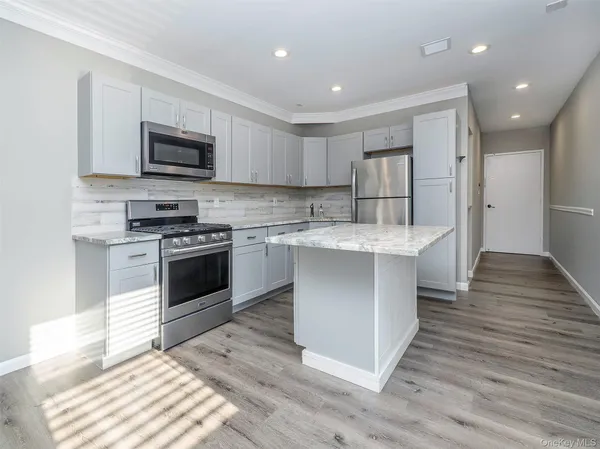 a kitchen with stainless steel appliances kitchen island hardwood floor sink and stove