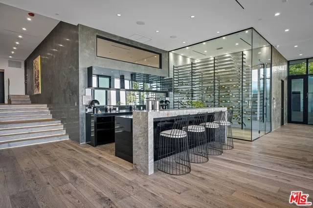 a kitchen with stainless steel appliances kitchen island granite countertop a refrigerator a stove a sink and a dining table with wooden floor