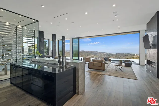 a living room with stainless steel appliances kitchen island granite countertop a sink and wooden floor