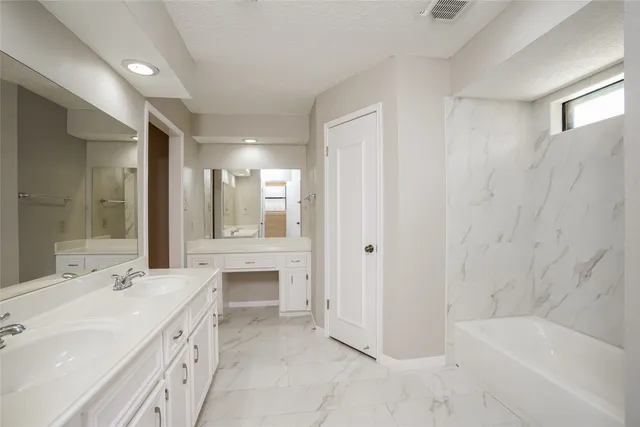 a bathroom with a tub sink and mirror