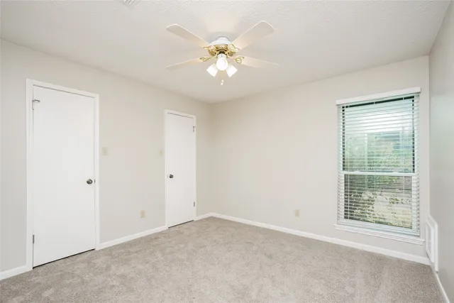 an empty room with a ceiling fan and a window