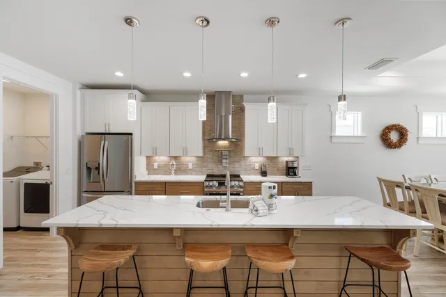 a kitchen with stainless steel appliances kitchen island granite countertop a dining table chairs and refrigerator