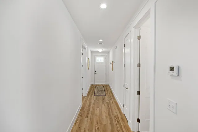 a view of a hallway with wooden floor and a bathroom