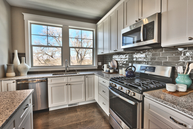 252 East Sandy Sage Way Sandy, UT 84070 - Photo 8 of 36 Kitchen featuring white cabinetry, stainless steel appliances, granite countertops, a subway tile backsplash, and wood-finish flooring
