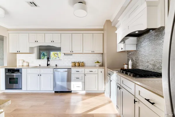 a kitchen with white cabinets and appliances