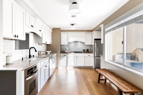 a kitchen with sink a stove and white cabinets