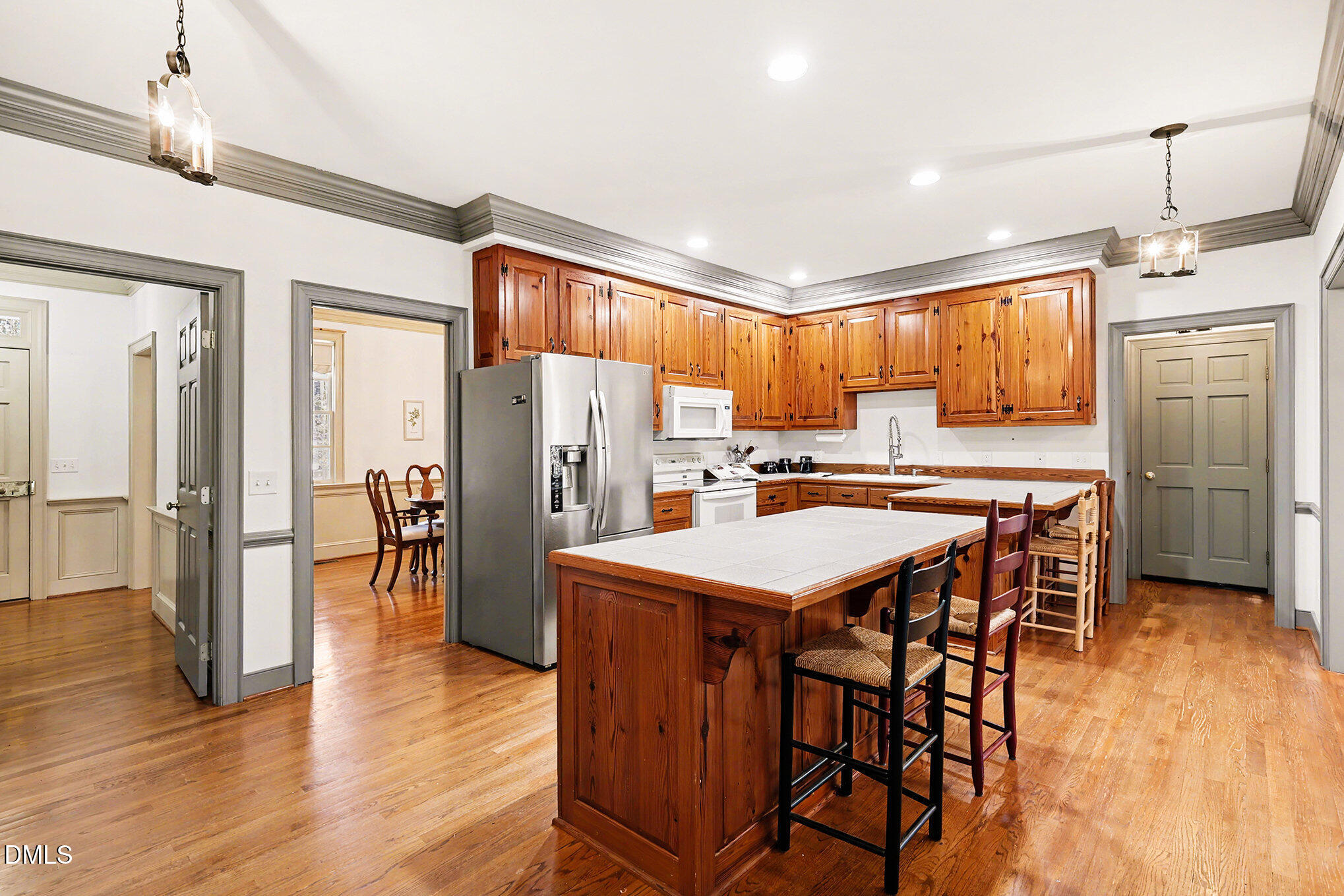 4604 Bartwood Drive Raleigh, NC 27613 - Photo 9 of 38 a kitchen with stainless steel appliances kitchen island granite countertop a refrigerator a stove a sink a dining table and chairs with wooden floor