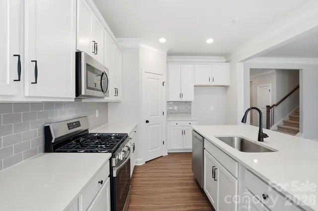 a kitchen with stainless steel appliances granite countertop a sink stove and white cabinets