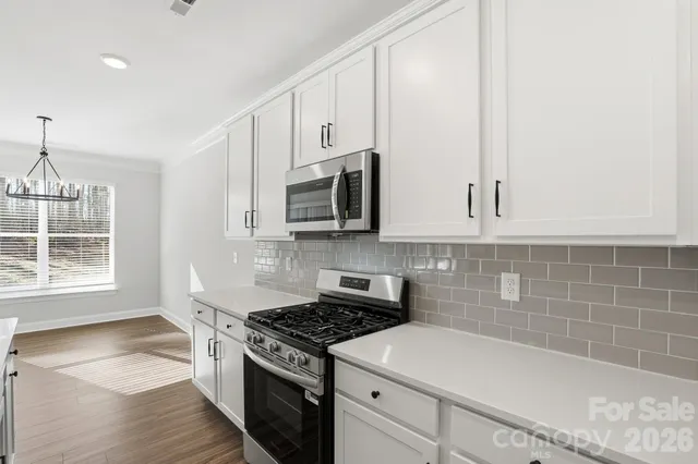 a kitchen with stainless steel appliances granite countertop a stove a sink and white cabinets
